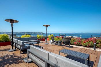 a deck with tables and chairs overlooking the ocean at Astro Apartments, Seattle, WA, 98109
